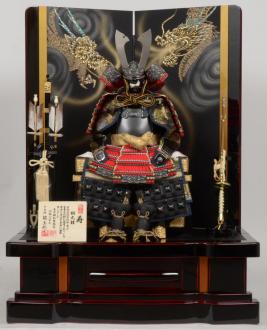 初陣の時に着る鎧の色合いが朱色である事から、特に人気の高い、中鍬形朱糸縅鎧の中床飾りです。台屏風には、曙塗りと呼ばれる研ぎ出し塗りを施し、特撰品に相応しい職人技を用いました。