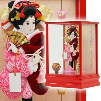 こちらの羽子板付き「聖美(赤)10号 正絹しぼり羽子板付」(カブセケース入り)は、正絹しぼり仕立てと、ベルベット地に桜柄刺繍がほどこされたお袖の、代表的なスタイルの柄の一つである「道成寺」です。
能の演目の一幕を模した舞い姿の優美な印象で、「将来幸せになれますように・・・」という意味合いがあるものです。
また、まり飾りは女の子の初正月を祝う羽子板に添えられる事の多いお飾りですが、ただ華やかさを増すためだけでなく、「丸く健やかに美しく育つように」との願いが込められています。
ケースのバックには、桜柄の刺繍がデザインされて、春らしいケース飾りです。
お子様の幸せを願うご両親の想いが込められた、女の子のお守りとして受け継がれてきた日本の伝統的縁起物です。