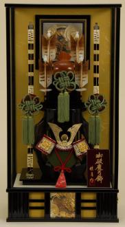 黒塗りケースの破魔弓飾りです。4本の矢と2本の弓に兜が入っている大変豪華な破魔弓飾り、ケース正面とバックには彫金が張られています。
