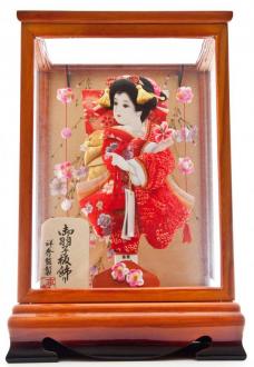 赤い絞りと可愛い桜刺繍の着物が華やかな羽子板です。両脇には可愛いつまみ細工のつるし物を配し、欅塗りの木枠のケースに入れました。ケース前面は面取りガラスとなっており、小型ながらボリューム感、見応えがある一品に仕上げました。